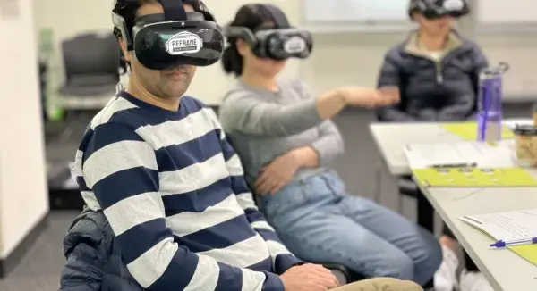Staff members with virtual reality goggles on in a classroom setting