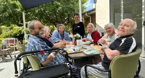 A group of older adults enjoying a meal outside together