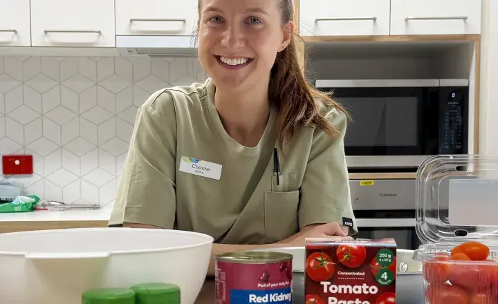 Supporting the community beyond the hospital. Dietitians smiling leaning on the kitchen bench with health food in front of her