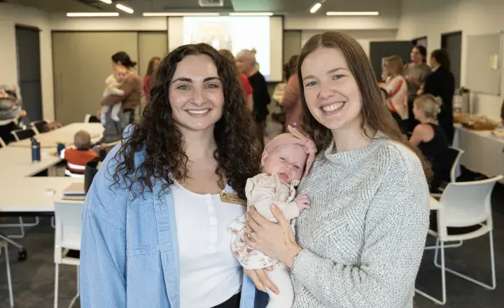 midwife and new mum with her daughter smiling at the camera