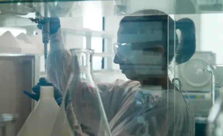 A person in safety gear works with lab equipment.