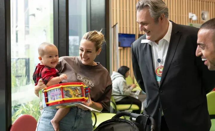 CEO Russell Harrison smiling with a community member and baby.