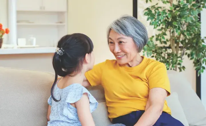 Grandmother and granddaughter on a couch smiling