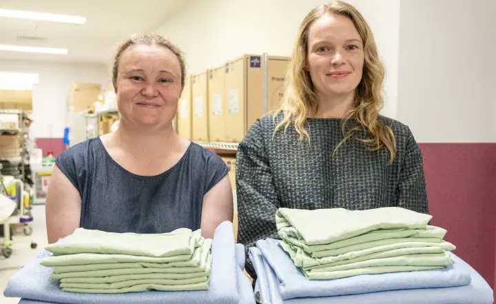 Western Health staff Kylie and Stacey holding linen in a hospital setting. 