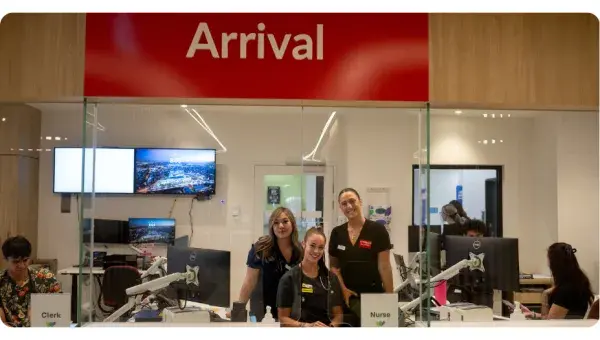 3 staff members under the Arrival sign in the emergency department.